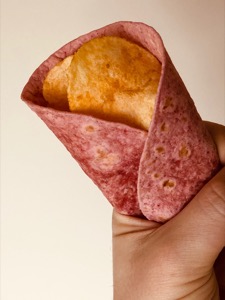 Close-up of crisps held in a pink tortilla wrap