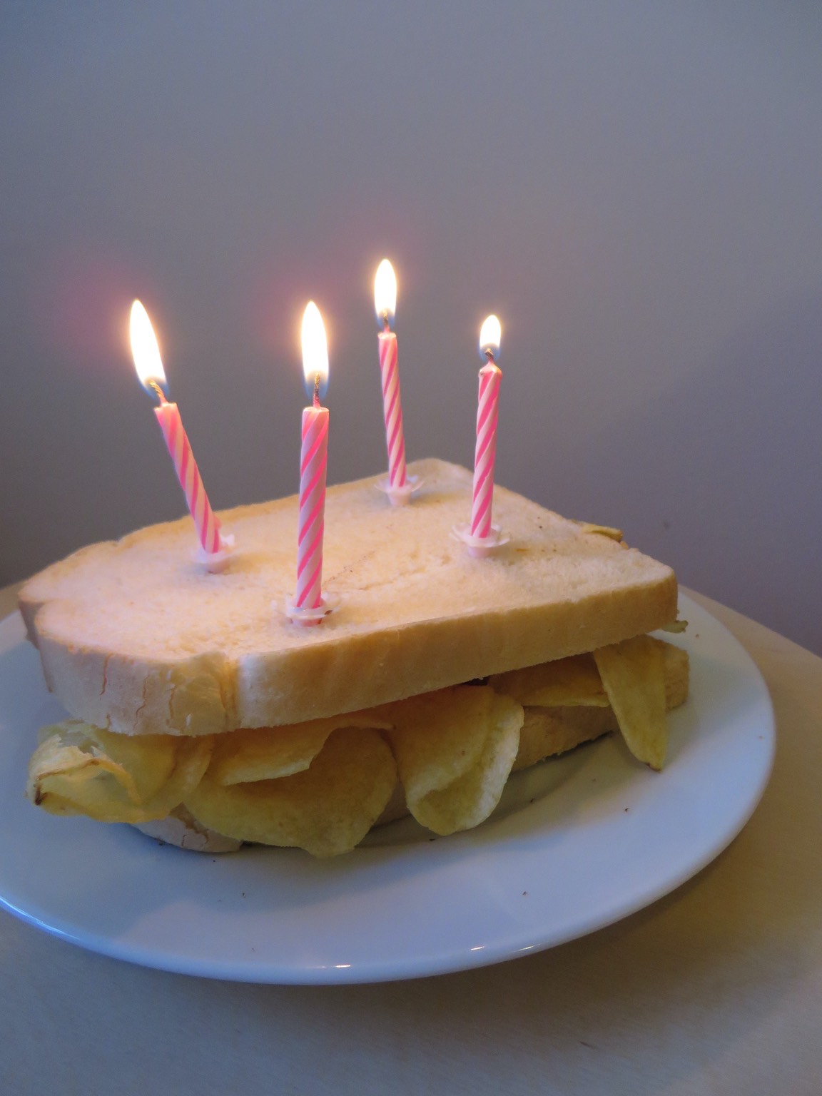 Four birthday candles on a white crisp sandwich