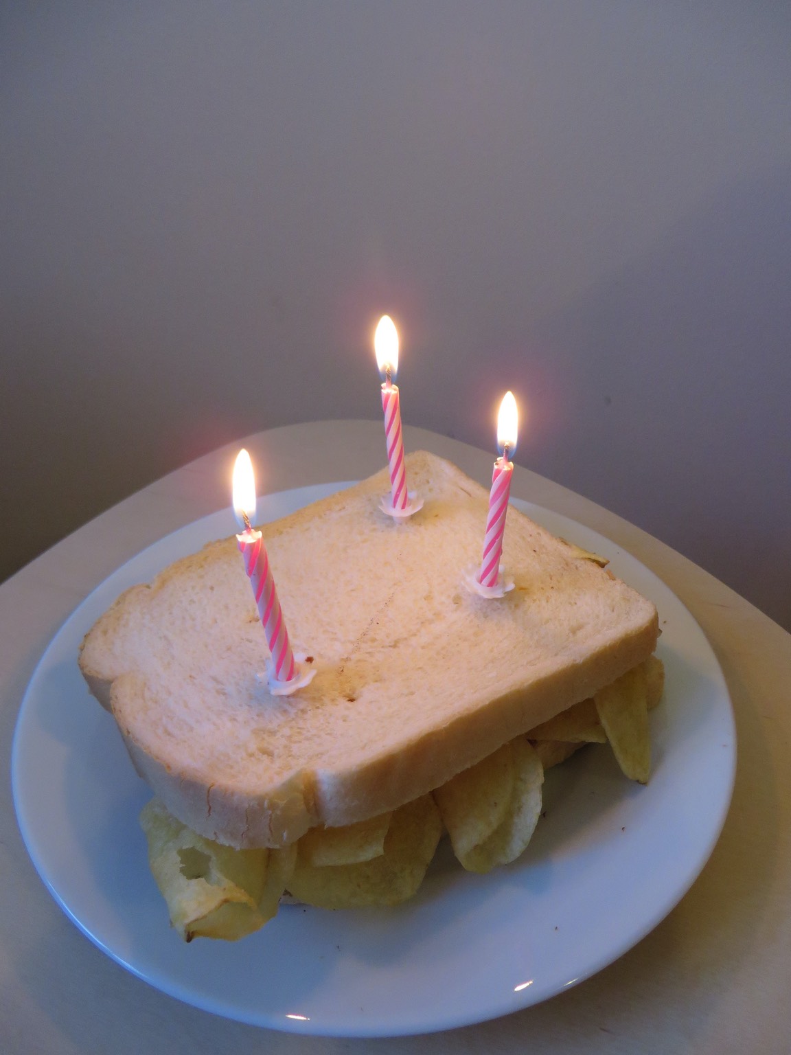 Three birthday candles on a white crisp sandwich