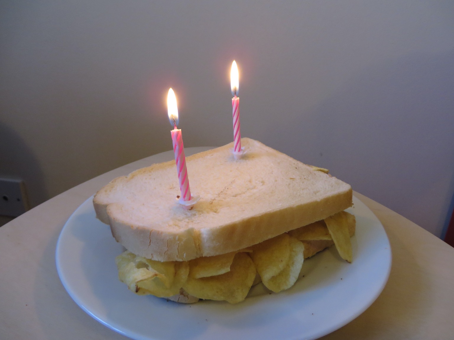 Two birthday candles on a white crisp sandwich