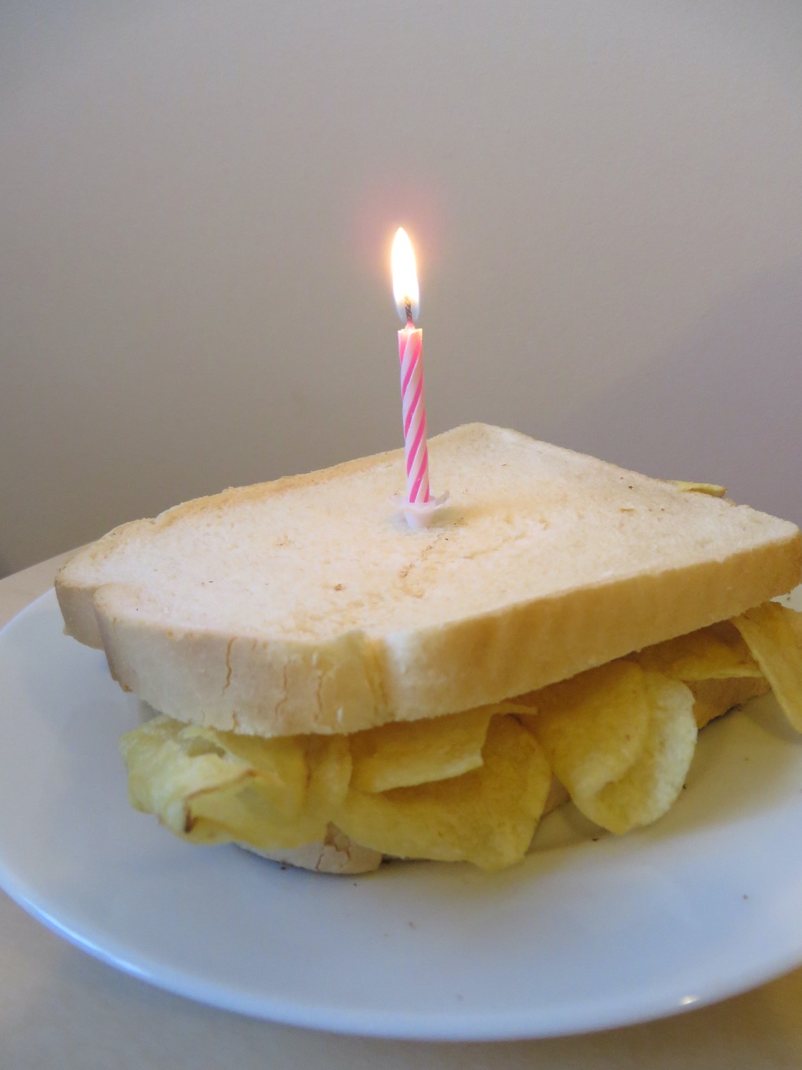 A birthday candle on a white crisp sandwich