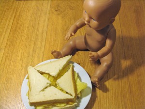 Quartered crisp sandwich alongside a doll