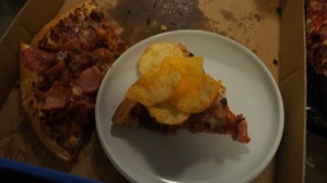 Crisps on pizza on a plate alongside more pizza