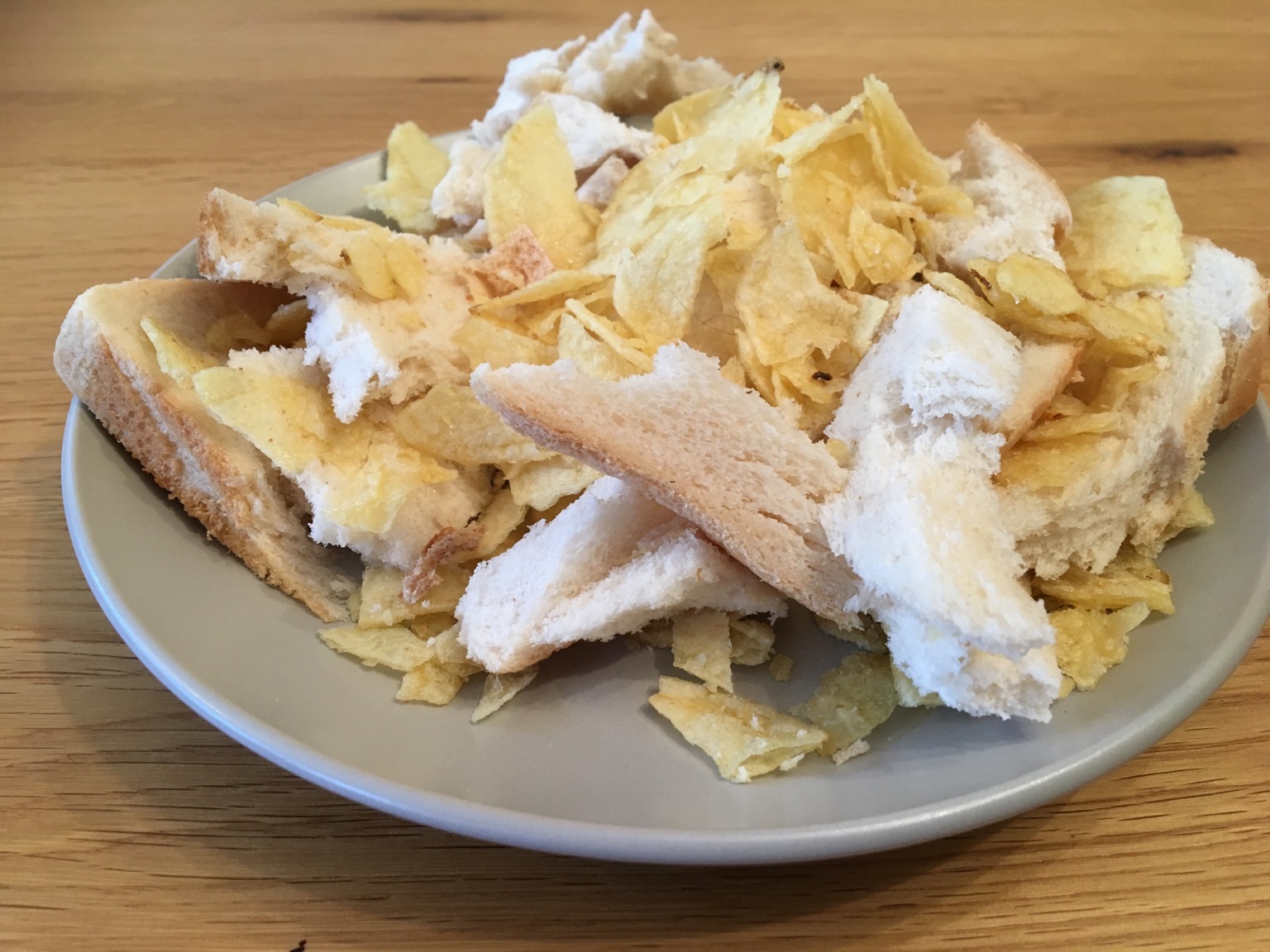 Torn bread and crisps heaped on a plate