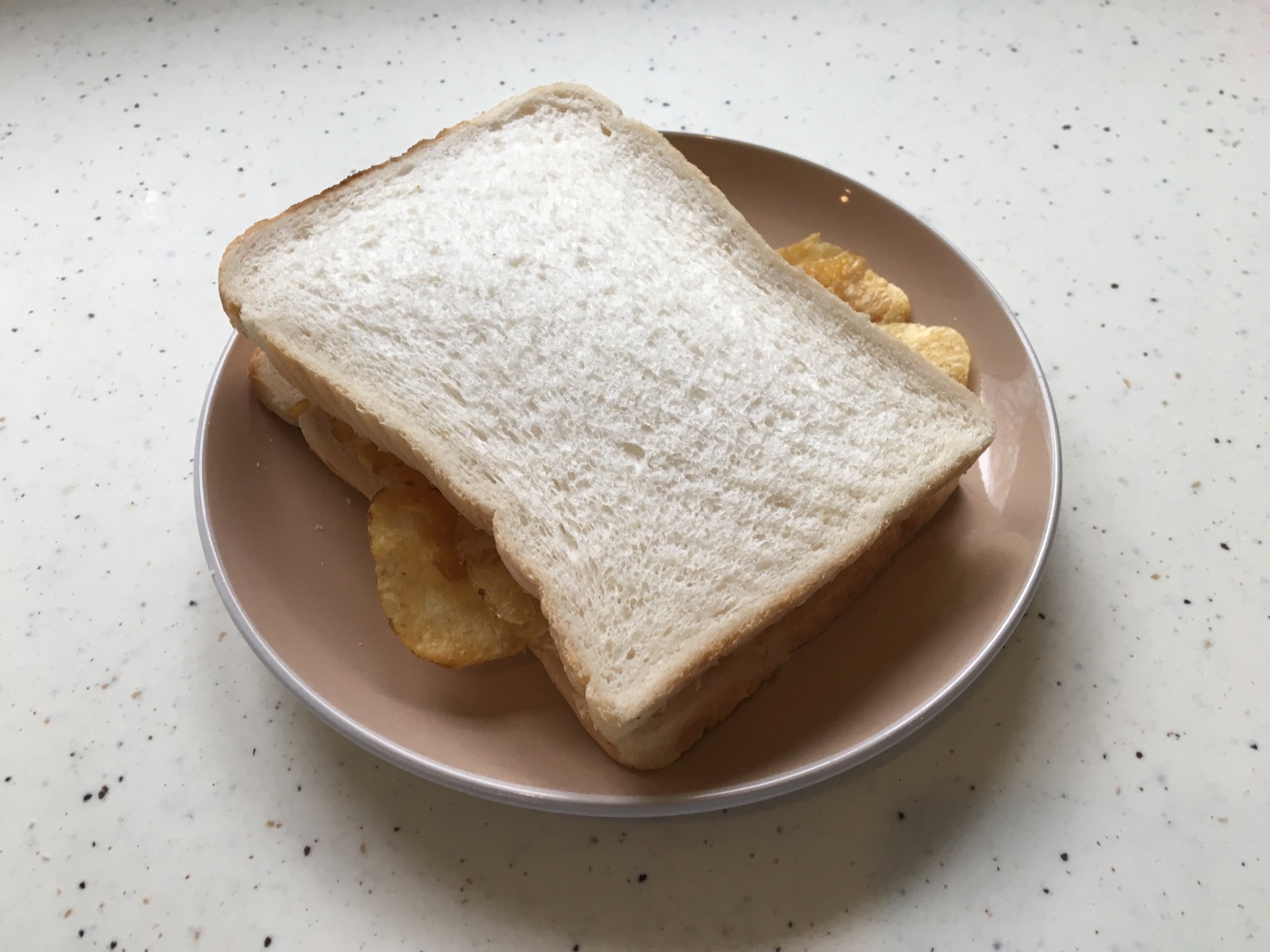 Two slices of white bread containing potato crisps