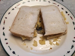 Sliced white bread containing crisps and cut in half